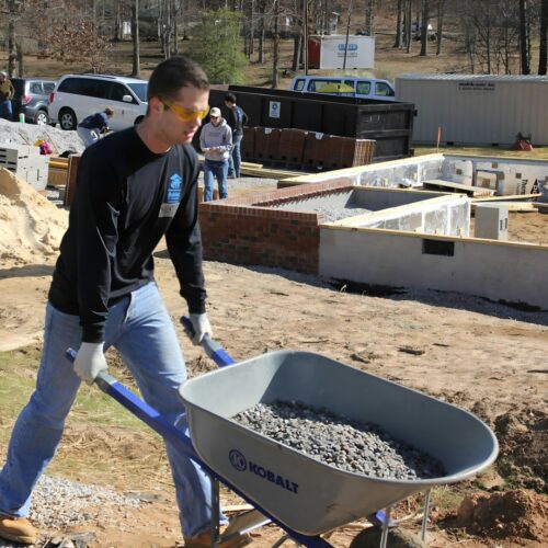 a man pushing a wheelbarrow filled with gravel